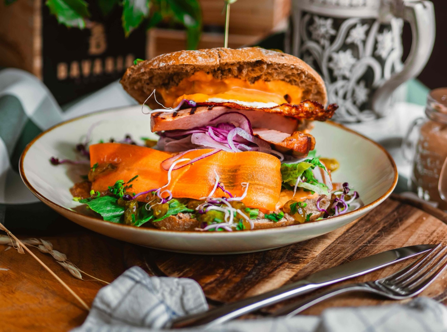 Leberkäse-Burger im Laugenbun mit Käse, Röstzwiebeln und Salat auf dem Teller